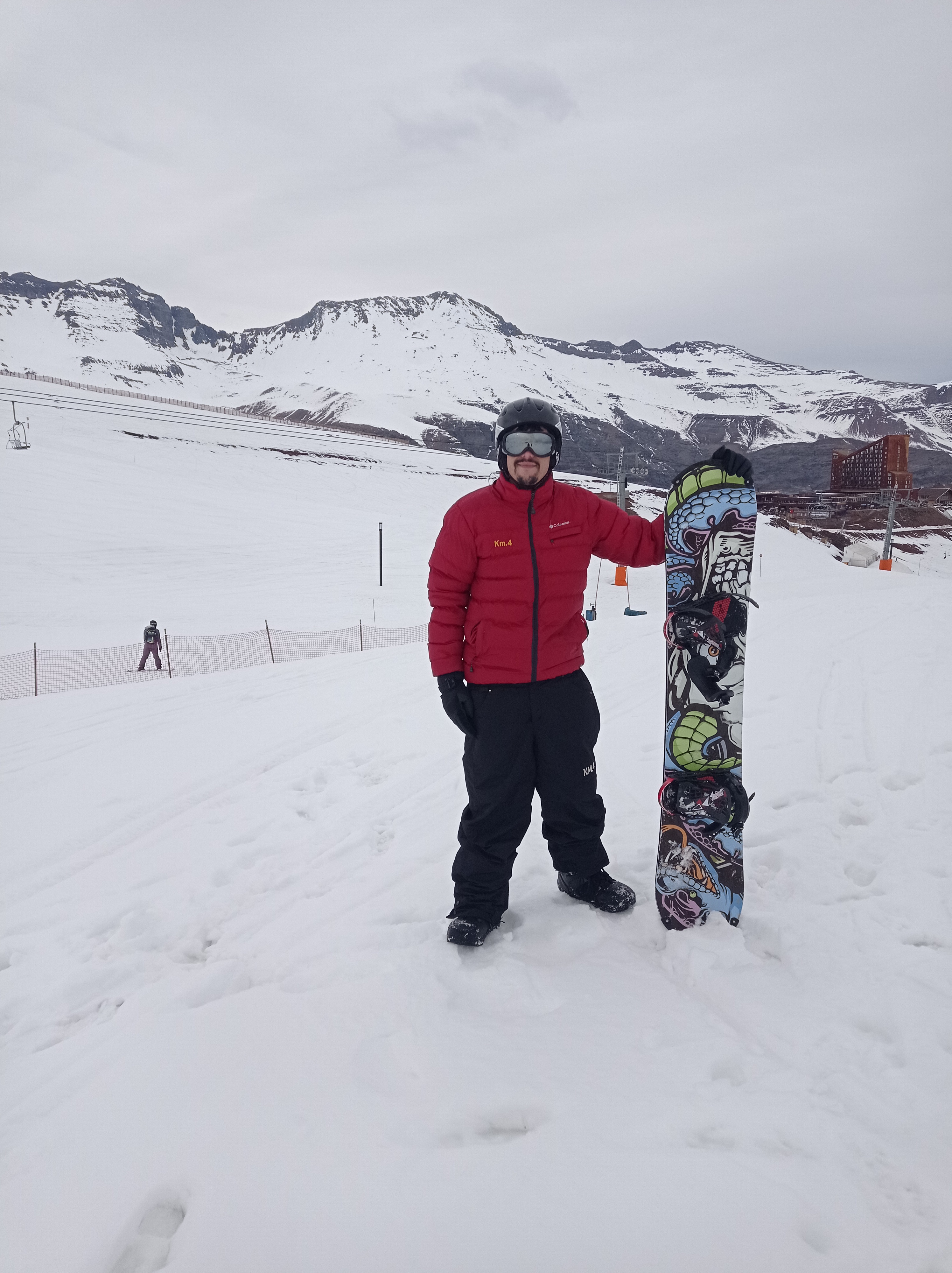 Isaac em uma montanha nevada segurando uma prancha de snowboard